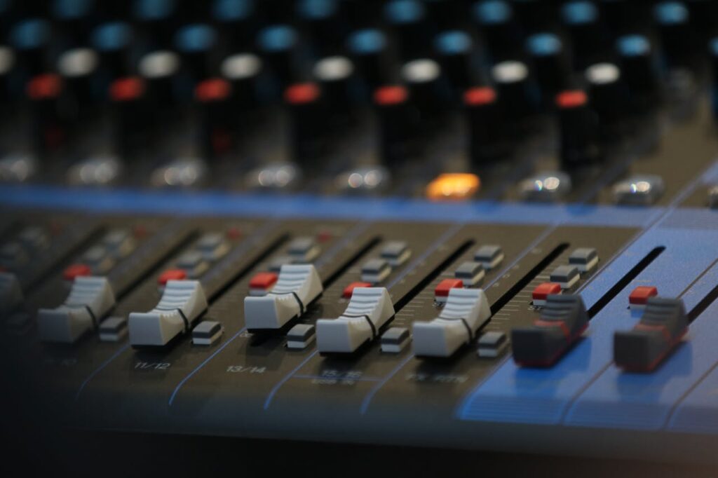 Close-up of an advanced audio mixing panel with slide controls and knobs in a studio setting.